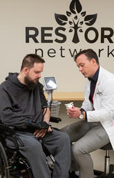 Dr. Aaron Phillips shows Nick Wiltshire the spine stimulation implant that will regulate his blood pressure.