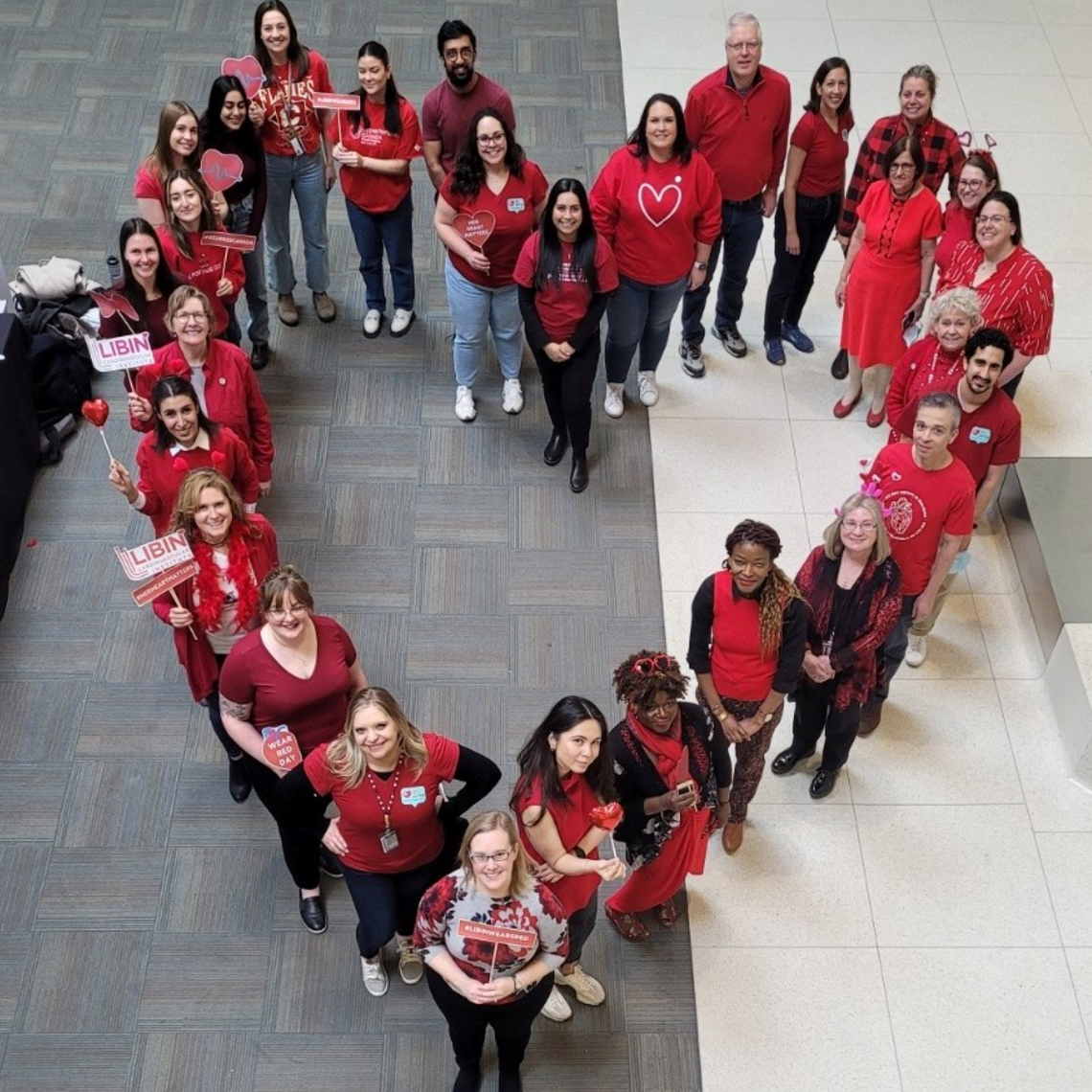 group of people wearing red and standing in the shape of a heart