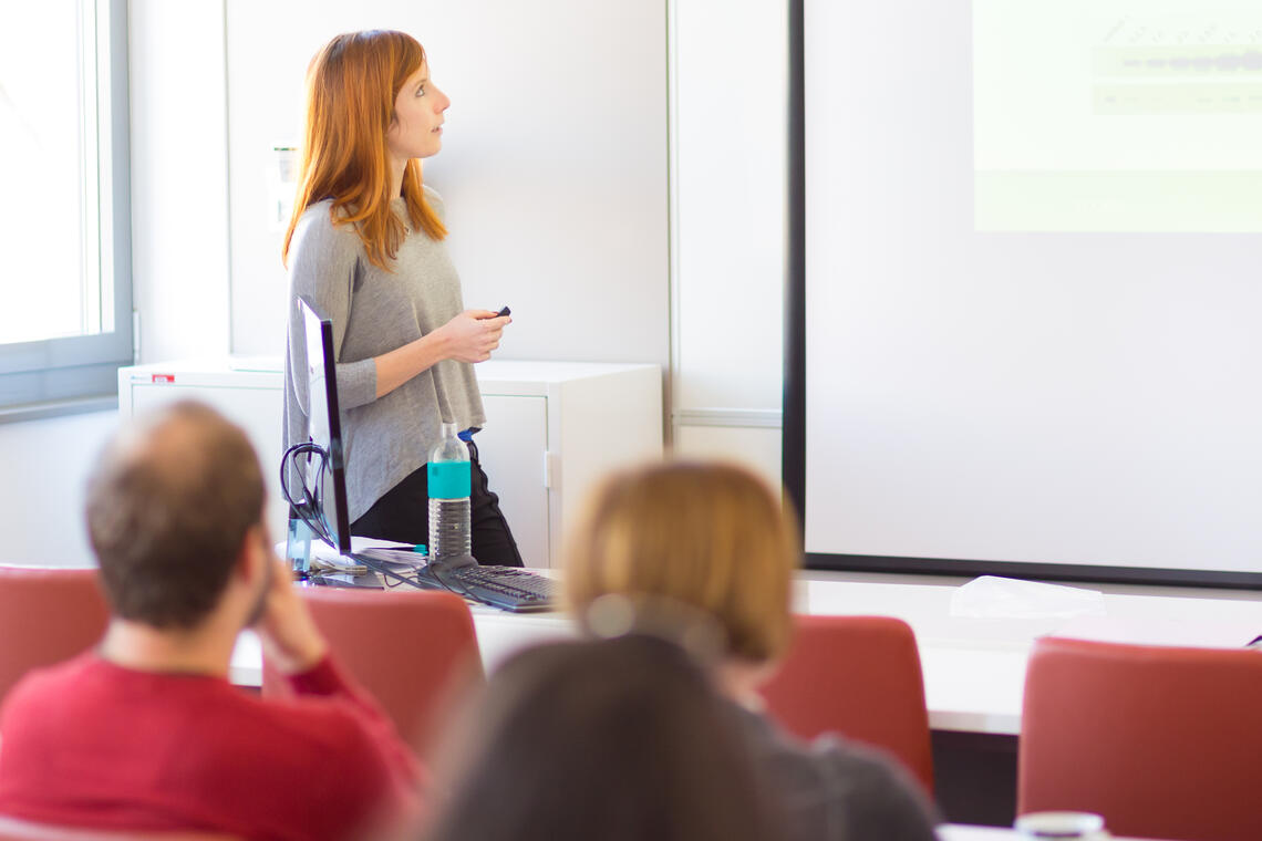 A woman presents information in front of a group of individuals