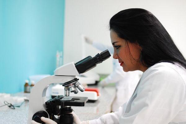 female researcher using a microscope