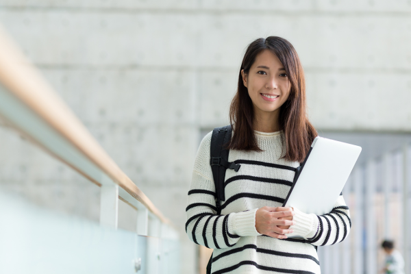 young woman holding a lap top in an university setting