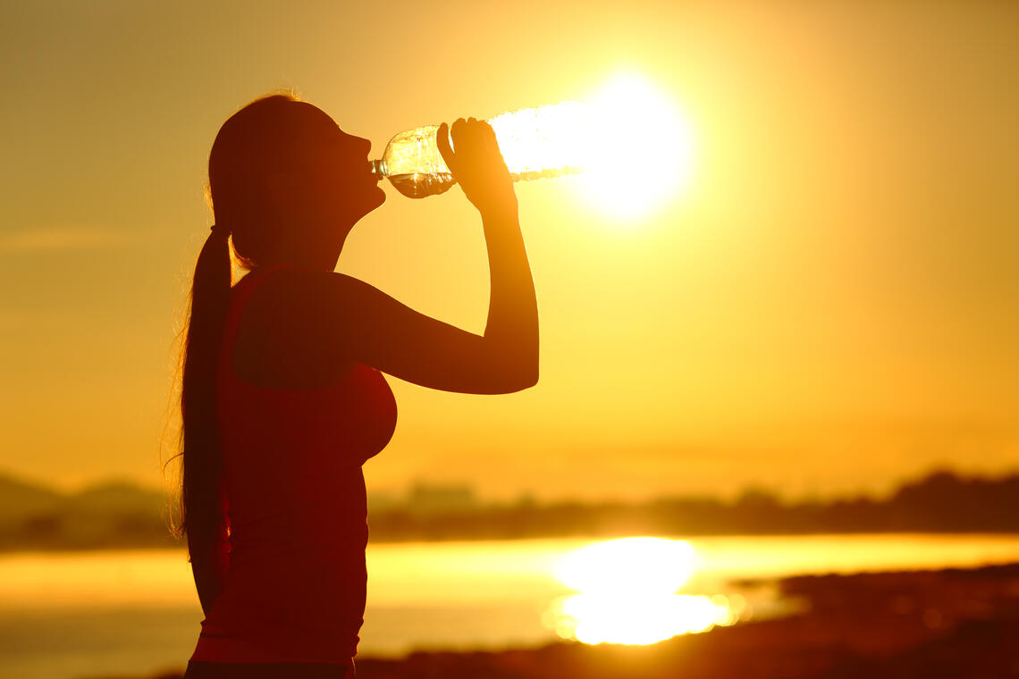 woman drinking water at sunset 
