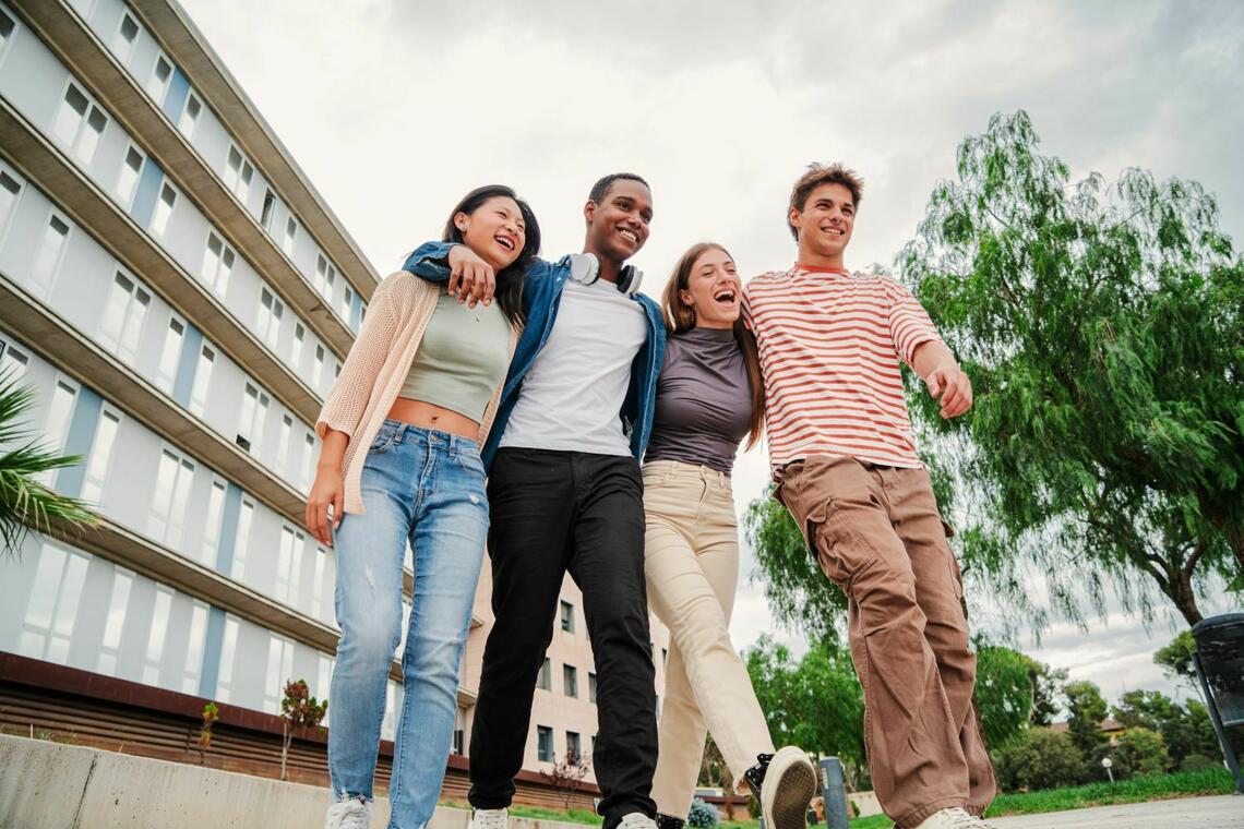 Students walk arm in arm outside campus building