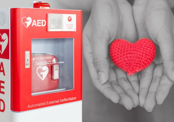 An AED next to a person holding a knitted heart
