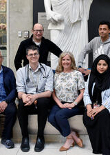 A group of people pose in front of a statue