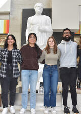 A group of students stands in front of a statute