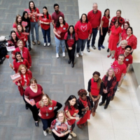 People wearing red standing in a shape of a heart